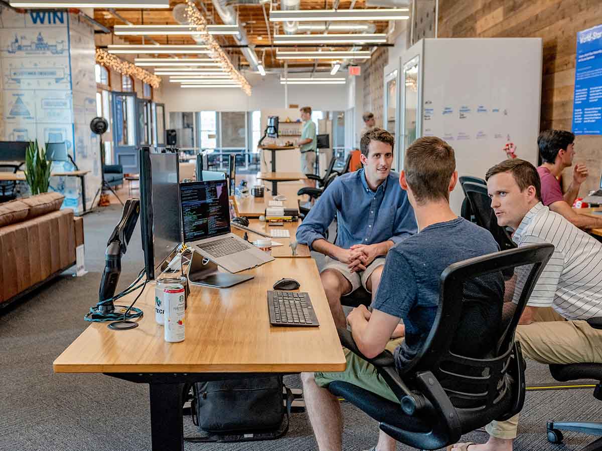 Developers collaborating at workstations, showcasing the WeBuildSaaS Advantage: cost-effective expertise on demand and transparent communication.