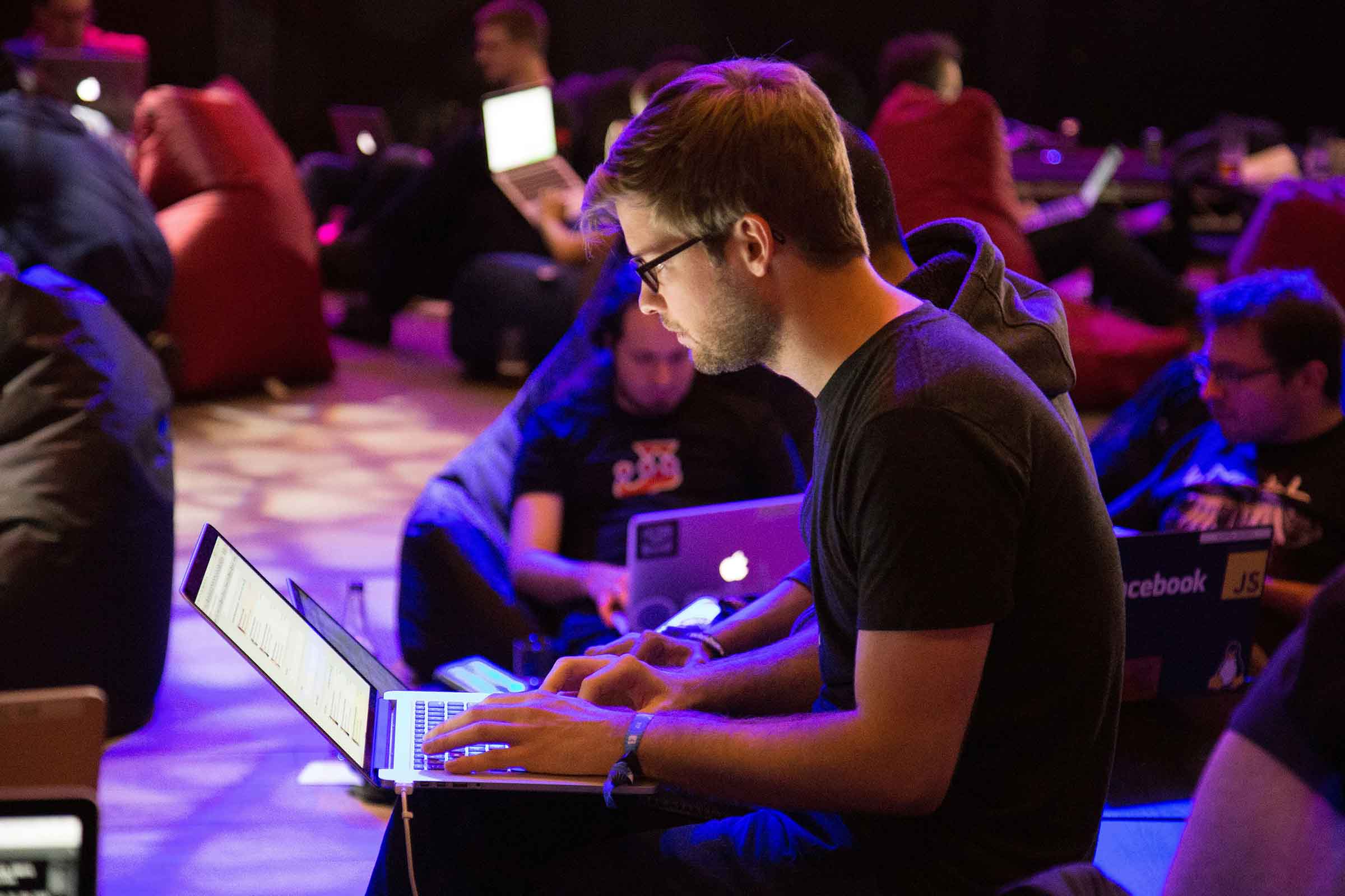 Community members collaborating at a conference with laptops, symbolizing the power of community-led growth in SaaS