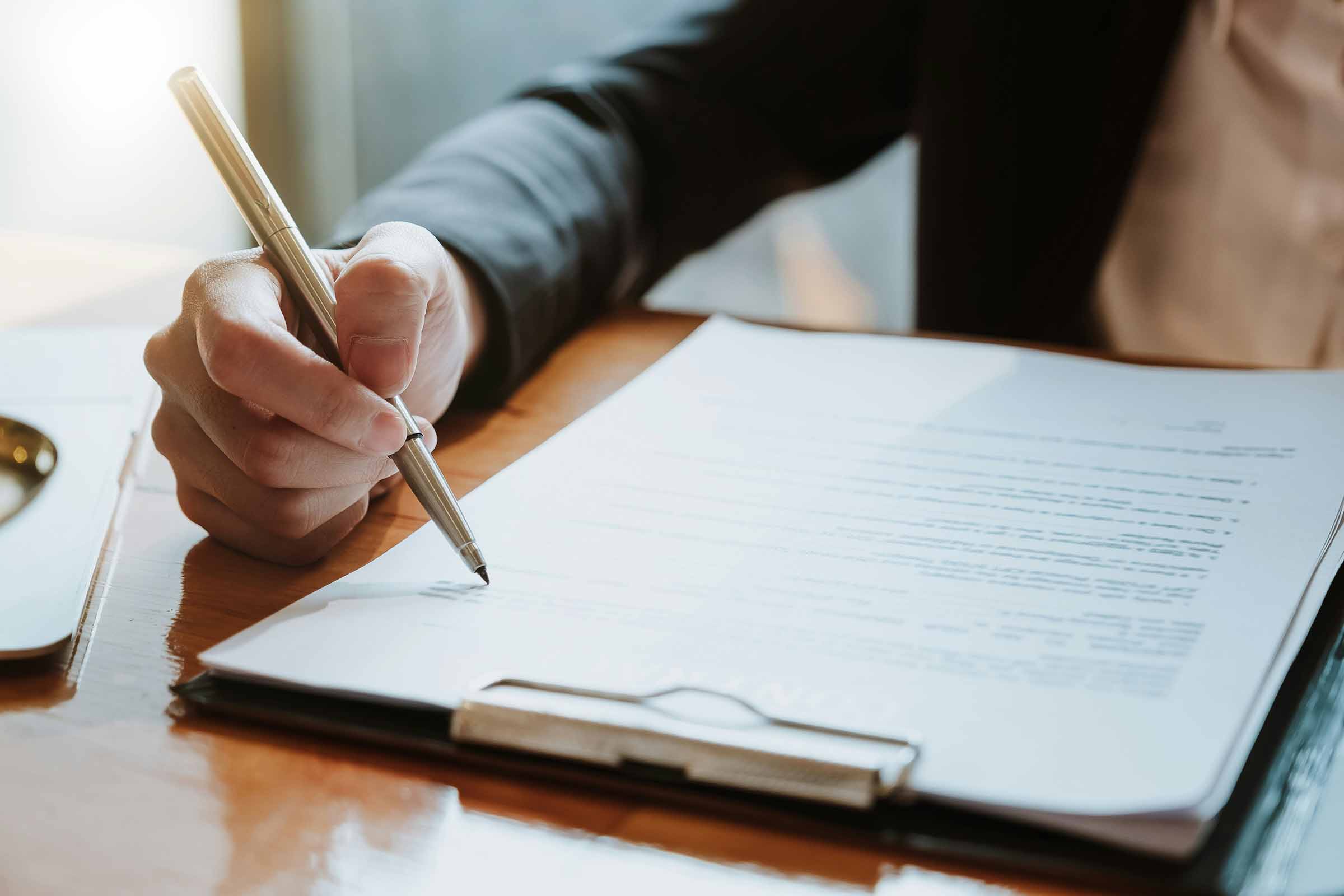 A hand holding a pen reviewing a contract document, representing the clear and fair terms of use for non-technical founders partnering with WeBuildSaaS.